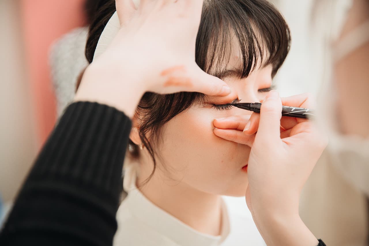 A beautician shaping a client’s eyebrow with a fine brush