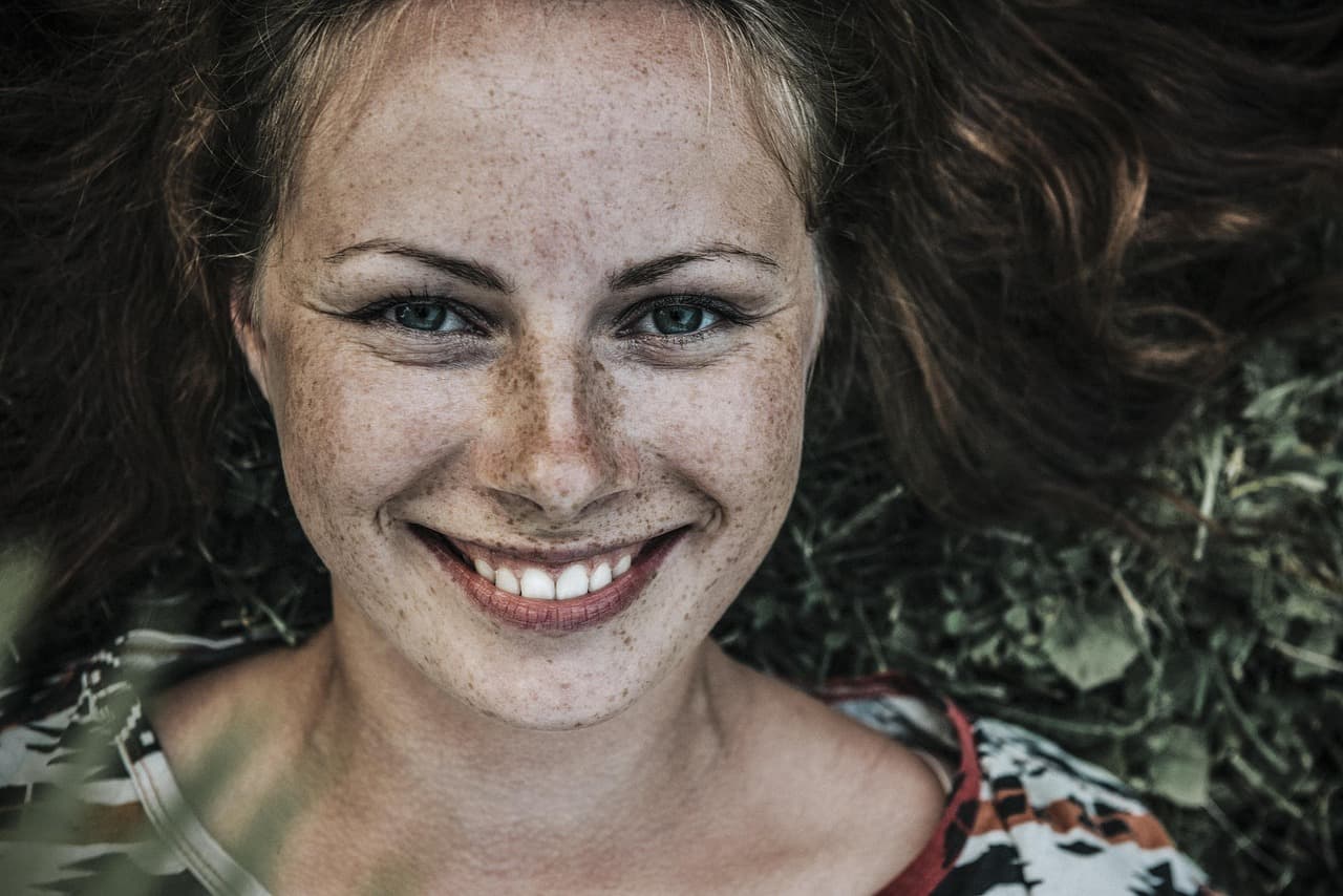 A smiling woman with freckles and natural brows